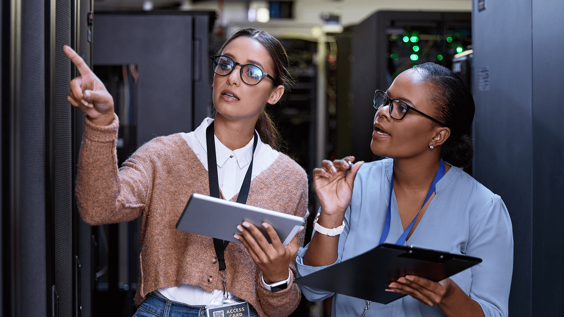 two technicians with a tablet and clipboard reviewing a server room