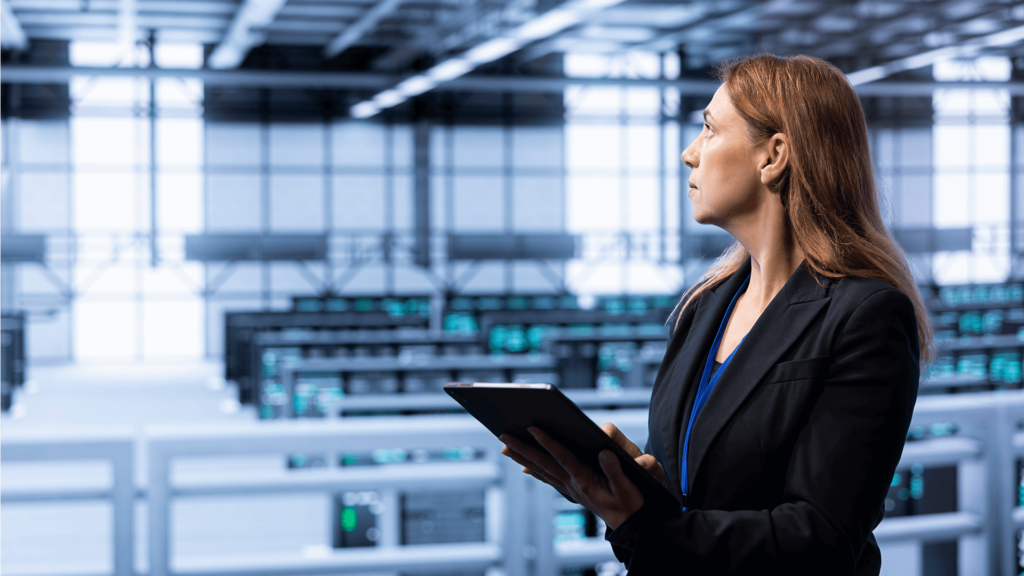 woman with a tablet overlooking a large data center